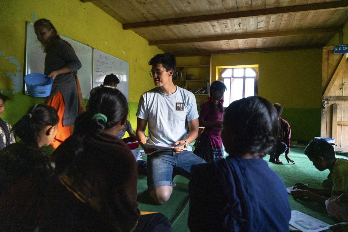 James Ricks '21 works with children in Odanaku, Nepal to plan a mural that represents health in their town.