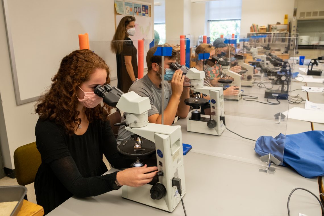 Students stay healthy in Geology Professor Lisa Greer&#039;s class by using their own microscopes, staying masked and sitting between plexiglass dividers.