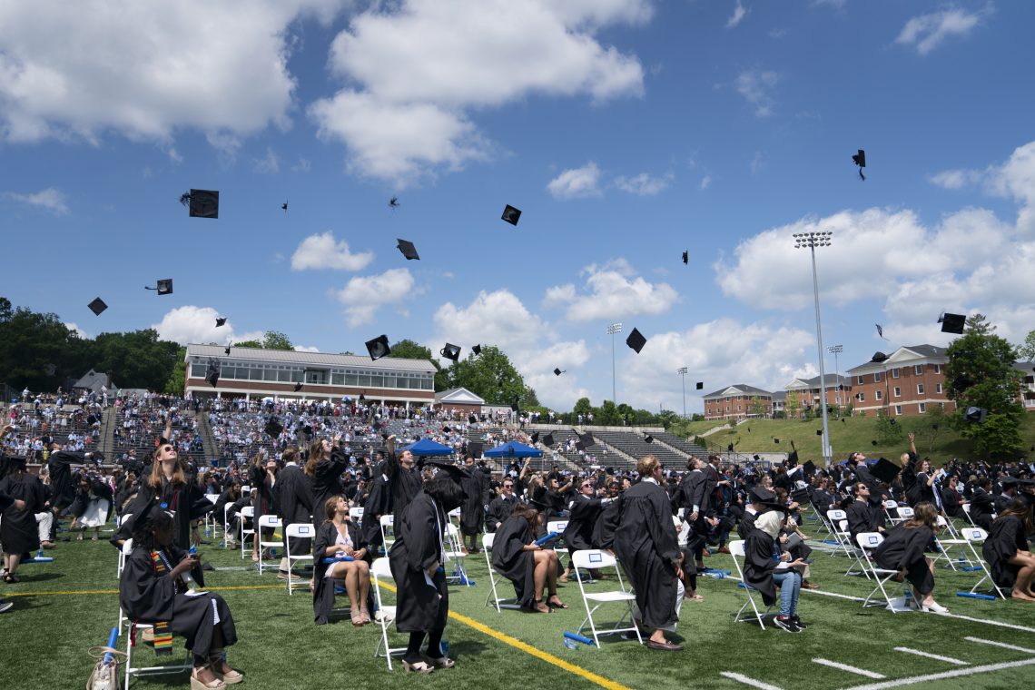 Graduates from the class of 2021 throw their graduation caps in the air