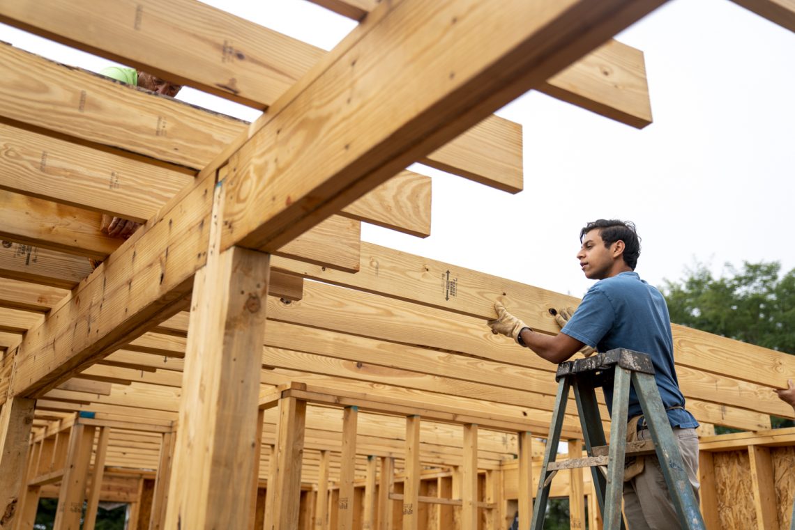 Neil Kansal ’25 places a rafter in a home while volunteering with Habitat for Humanity as part of the Volunteer Venture pre-orientation trip.