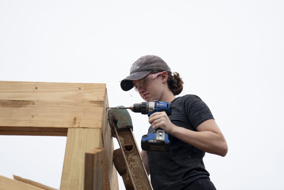 Ashley Shugart ’22 drills a hole while volunteering with Habitat for Humanity as part of the Volunteer Venture pre-orientation trip.