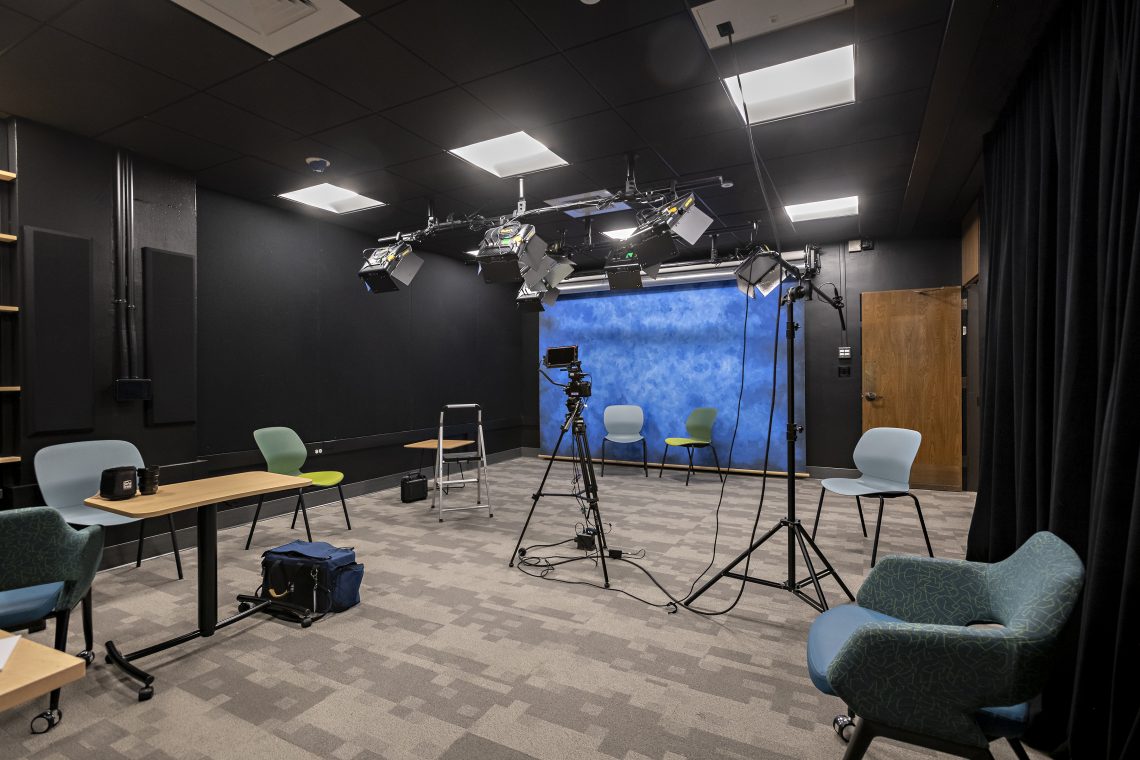 The high-tech video recording studio offers a dedicated space for video projects and can be reserved by anyone in the university community. It features multiple backdrops, including a green screen, and adjustable lighting. Outside the recording studio are three video editing suites, which can also be used for recording audio, such as podcasts.