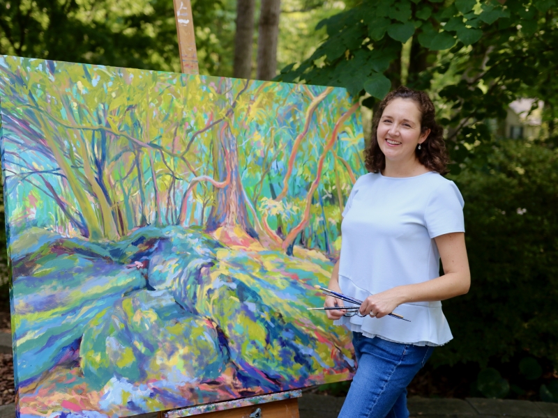 Katie Wall Podracky poses with one of her paintings from The Carolina Collection.