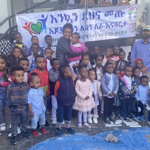 Melos Ambaye &#039;25 poses with children involved with Amen Charitable Organization.