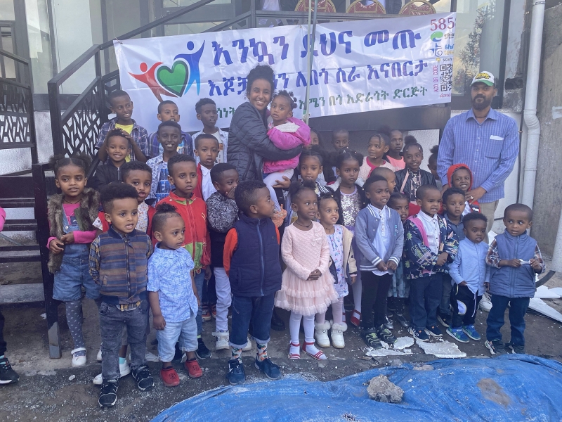 Melos Ambaye &#039;25 poses with children involved with Amen Charitable Organization.
